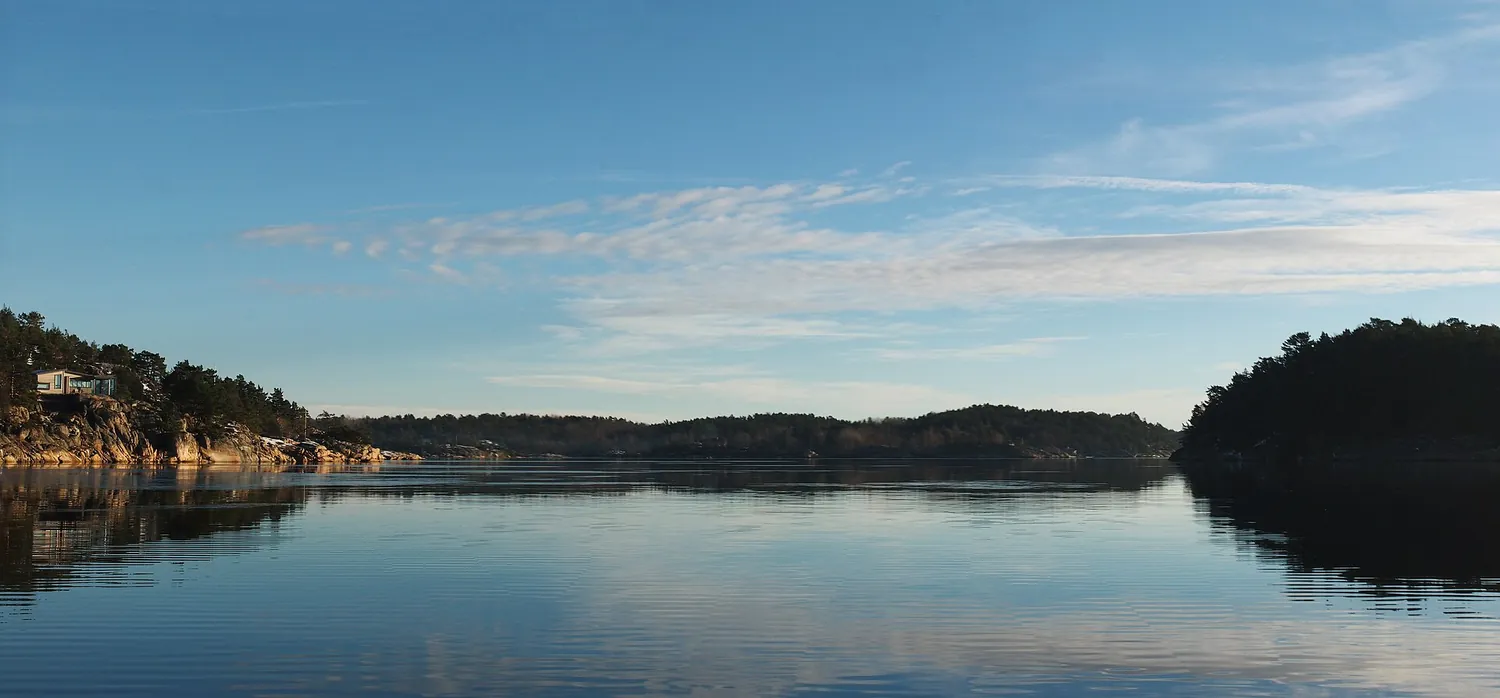 Rolig skjærgårdslandskap med holmer og speilblankt vann på Sørlandet