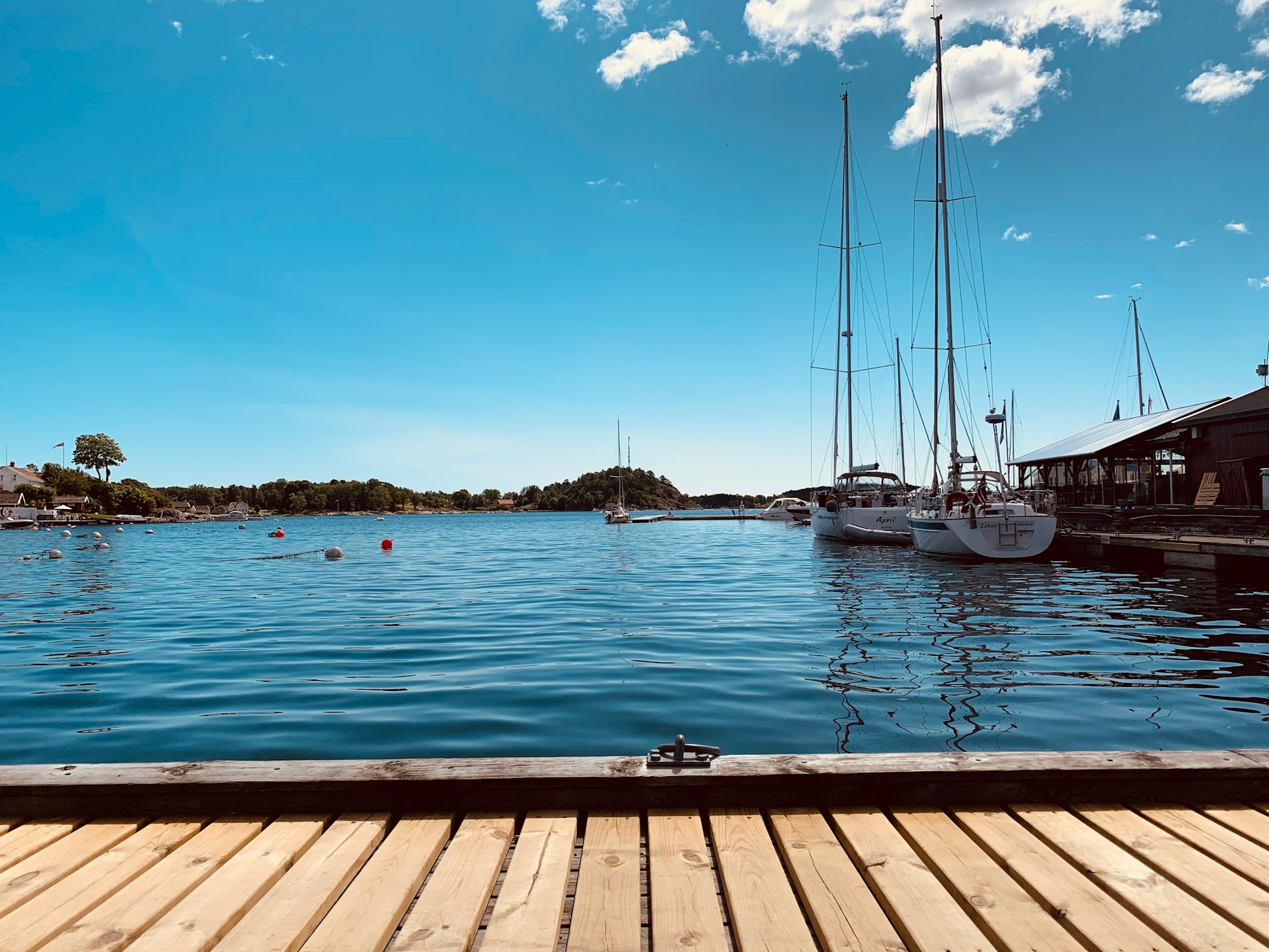 Seilbåter fortøyd ved trebrygge i Grimstad havn, stille sommervær
