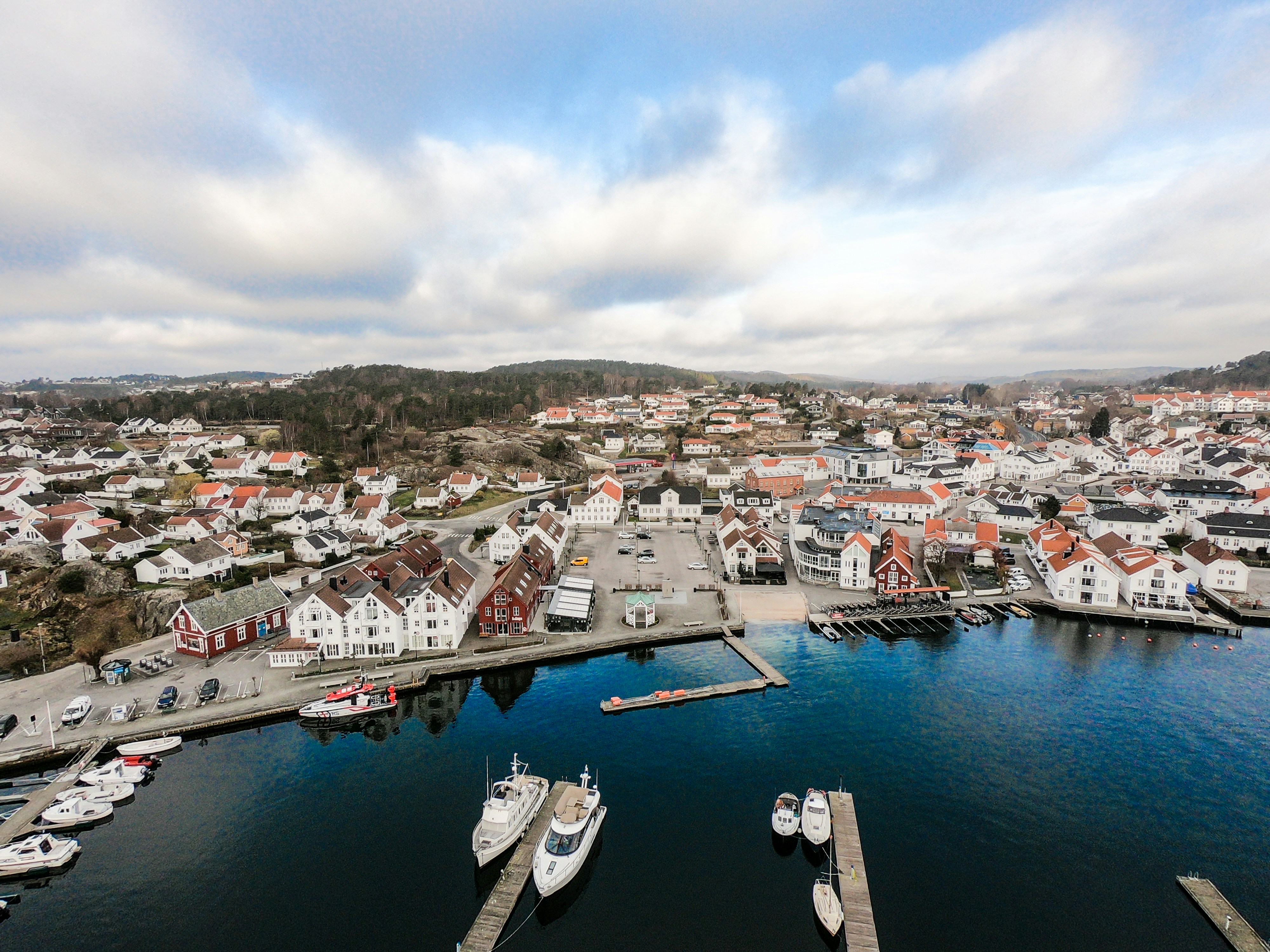 Luftfoto av sørlandsk kystby med havn og hvite hus