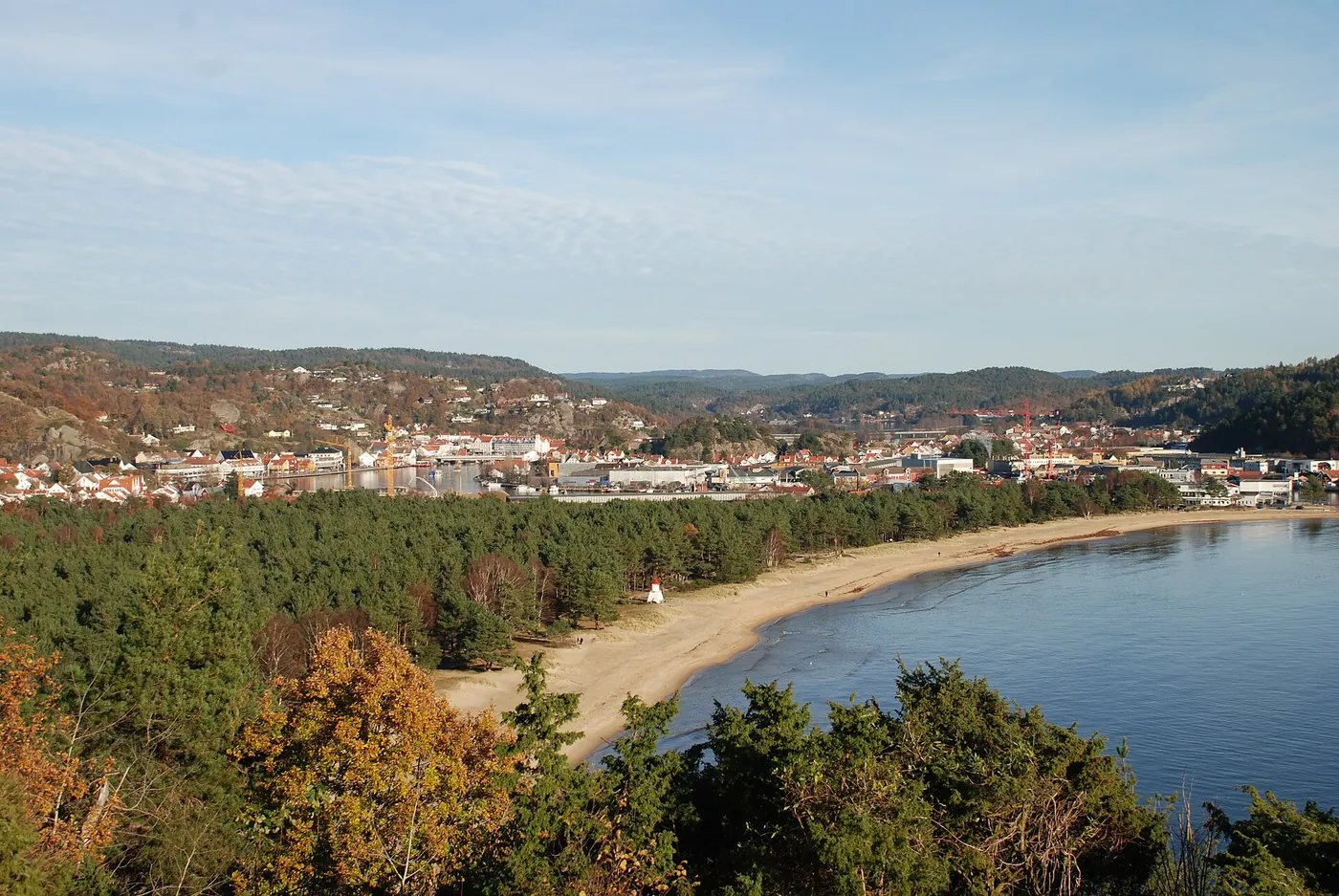 Luftfoto av sørlandsk kystby med havn og hvite hus